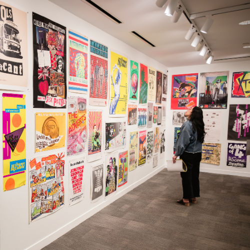 Woman looks at music posters on the wall of the Hawn Gallery during the Torn Apart exhibit