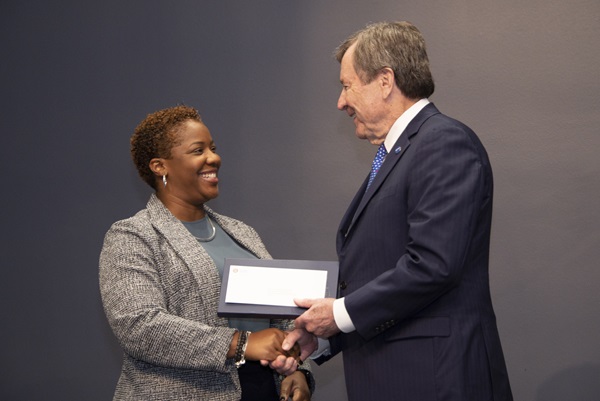 Janille Smith-Colin receiving a small box, letter and handshake from President Turner