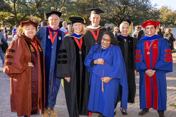 A group of faculty in academic regalia smiling for the camera