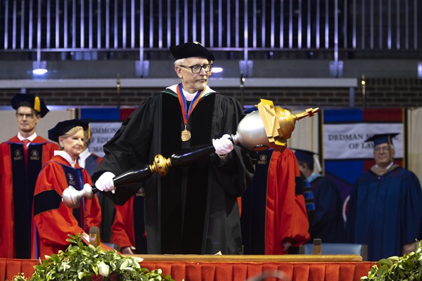 Faculty member holding a ceremonial staff at graduation
