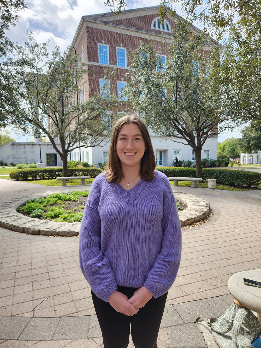 Alumna Courtney Kelly sits outside Caruth Hall