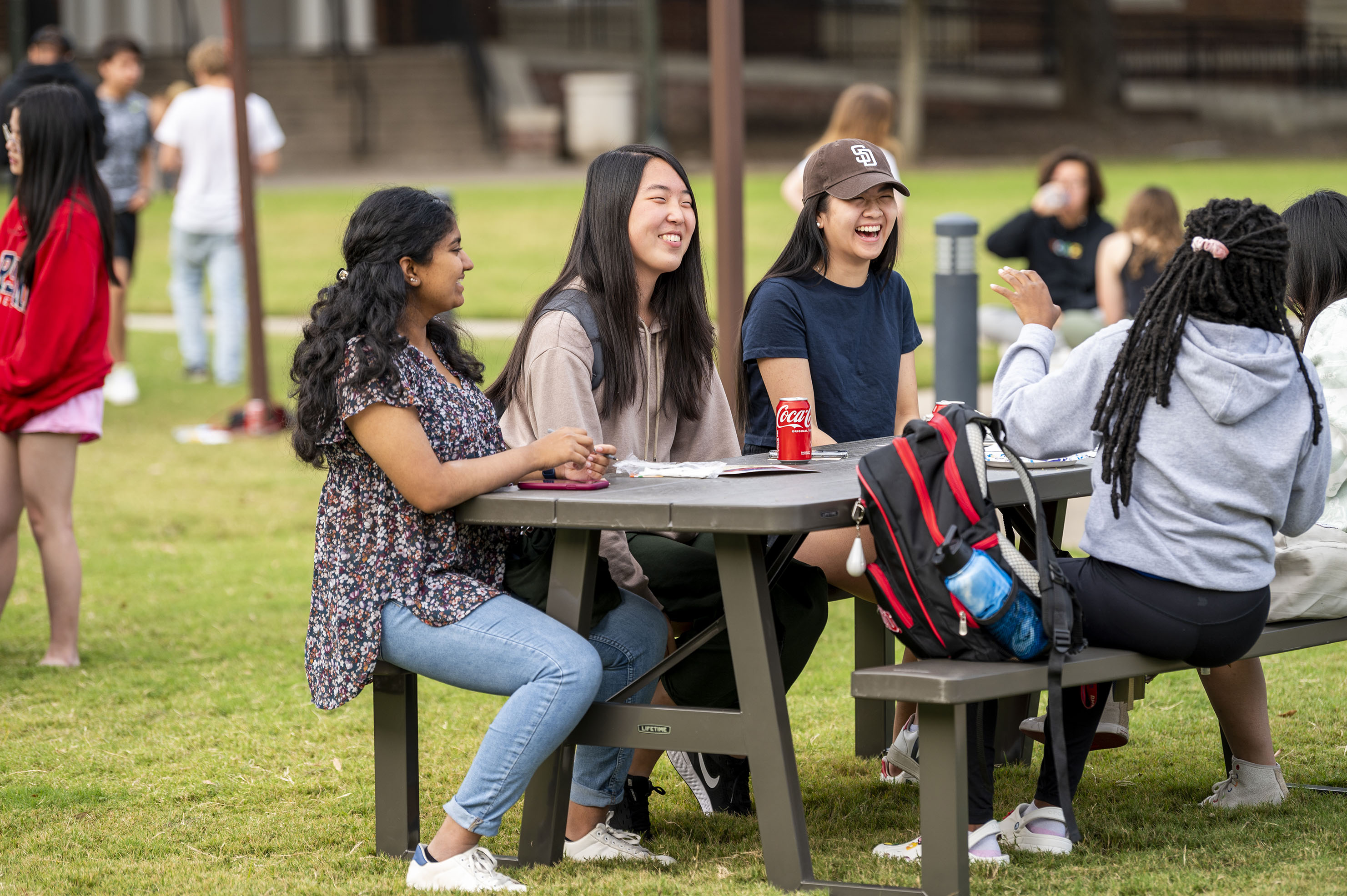 People laughing and sitting at a picnic table. 