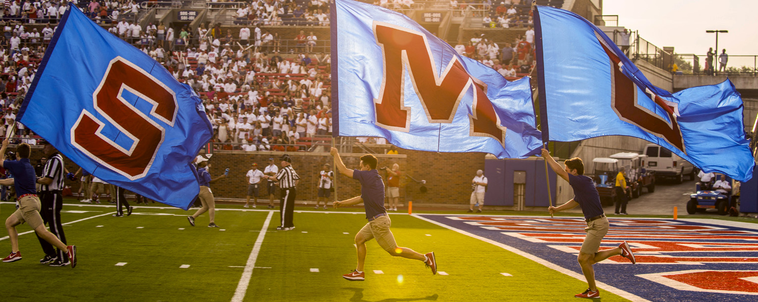 SMU cheer group running near fans at a football game.