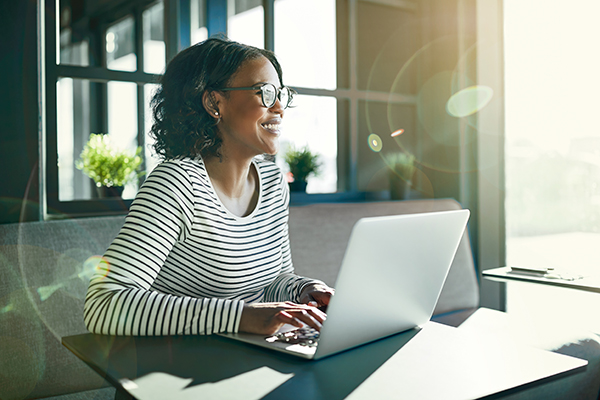 Woman working at a laptop in front of a window