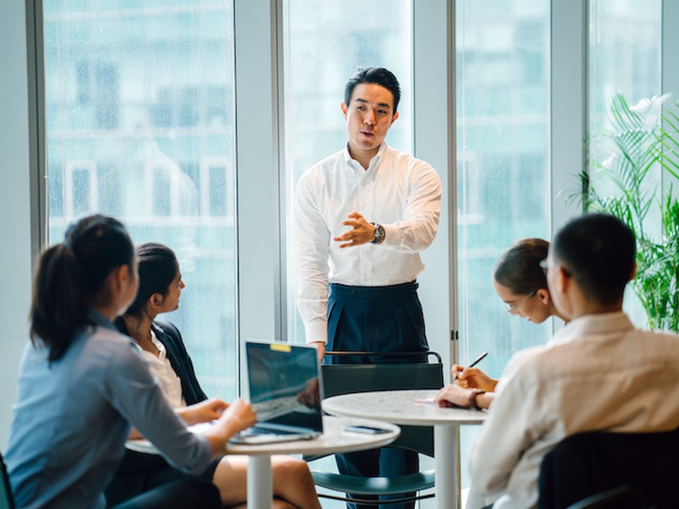 A group of business professional meet in a glass-walled conference room