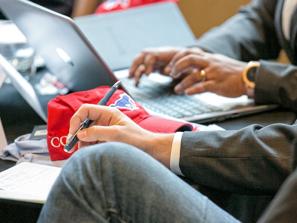 Two SMU Cox students sit together while working on a laptop