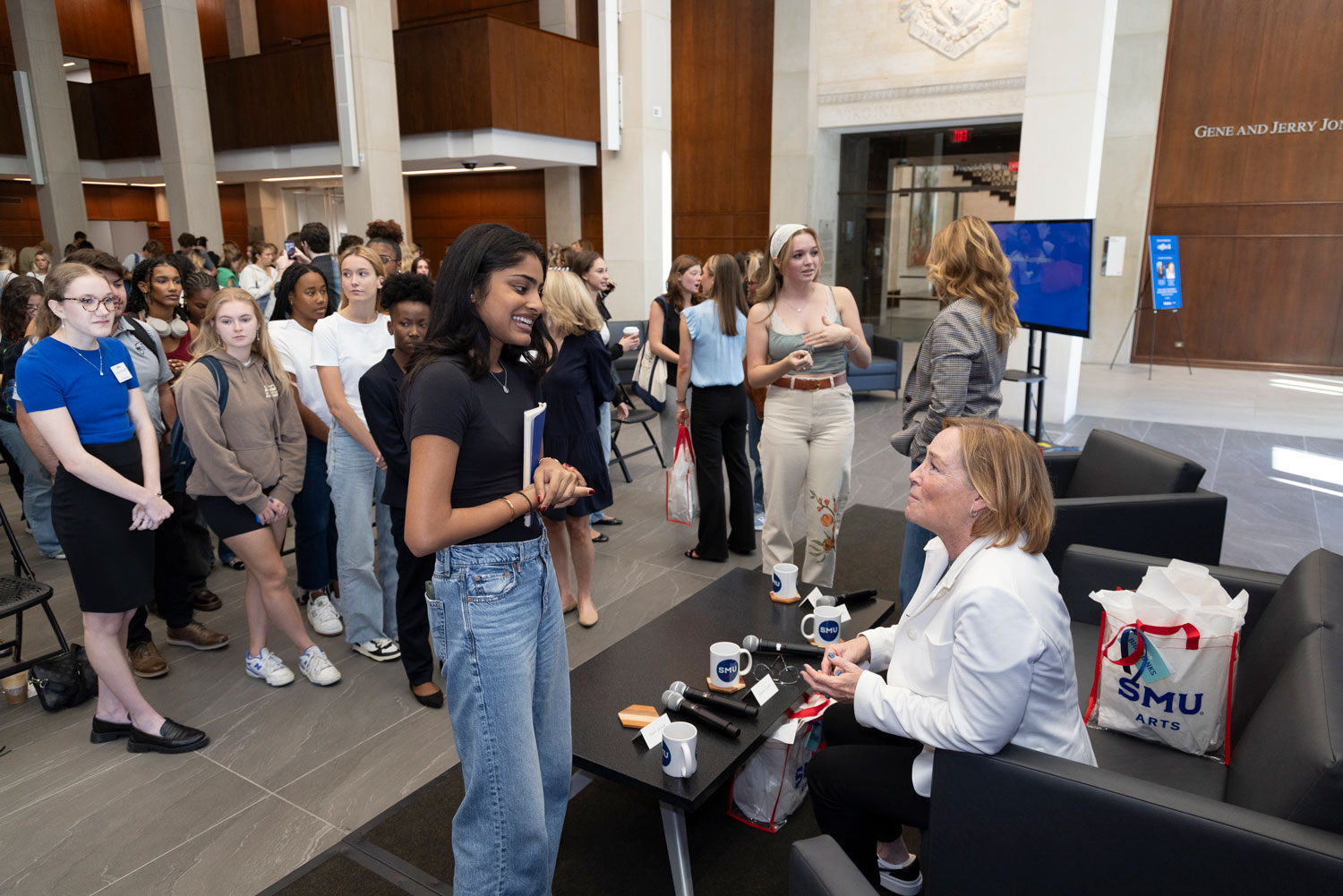 An executive board member speaks with a student on stage after their panel