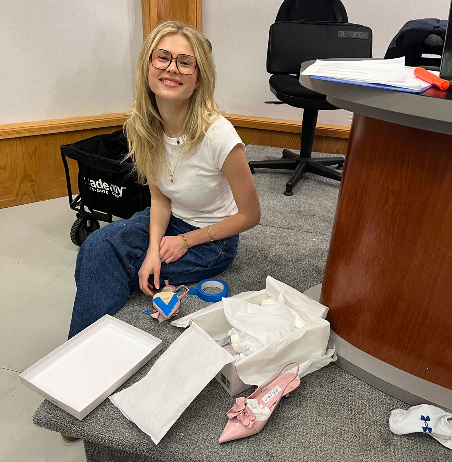 Fashion Media student Ellie Cogan works on set taping shoes for protection during photo shoots.