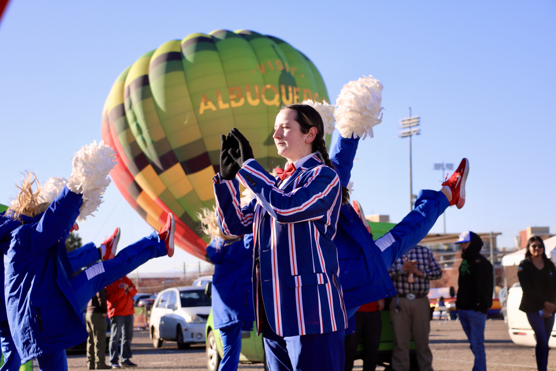 Mustang Band leader with cheerleaders outside in front of hot air balloon