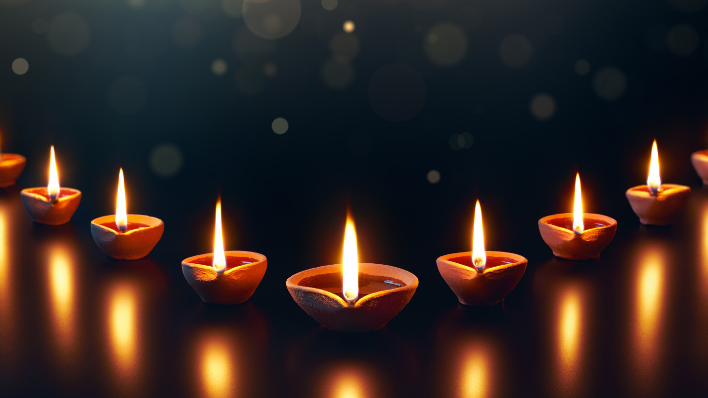 row of small candles in a "v" shape with flame on a black background