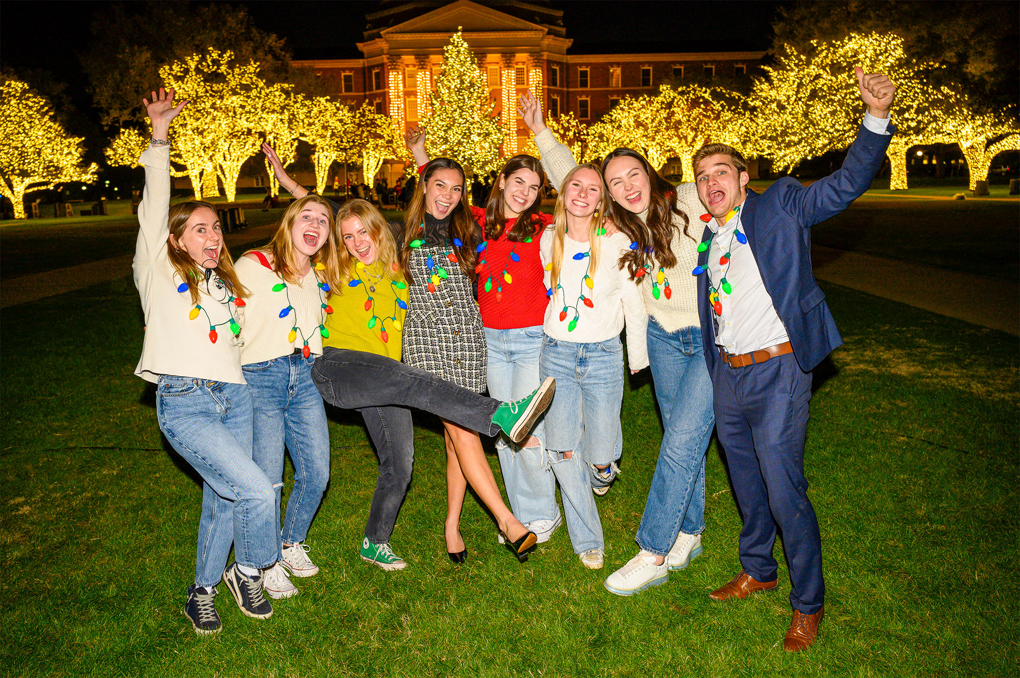 eight students celebration on dallas hall lawn in front of christmas tree at celebration of lights