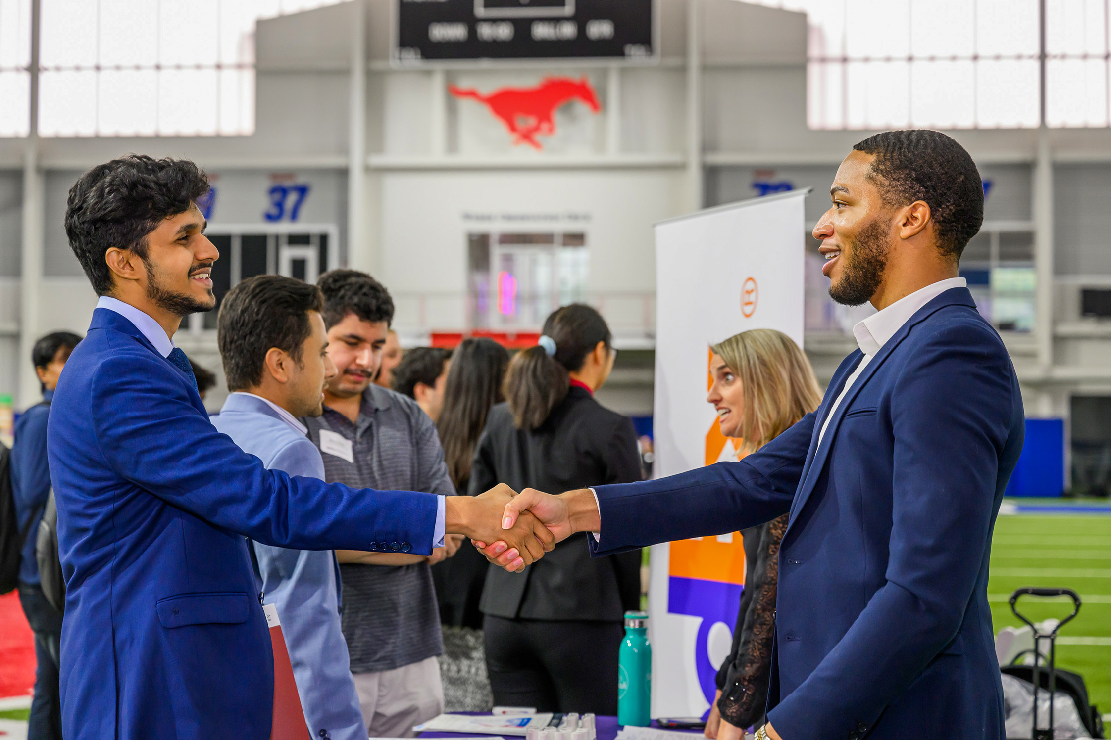 two men shaking hands in front of people talking