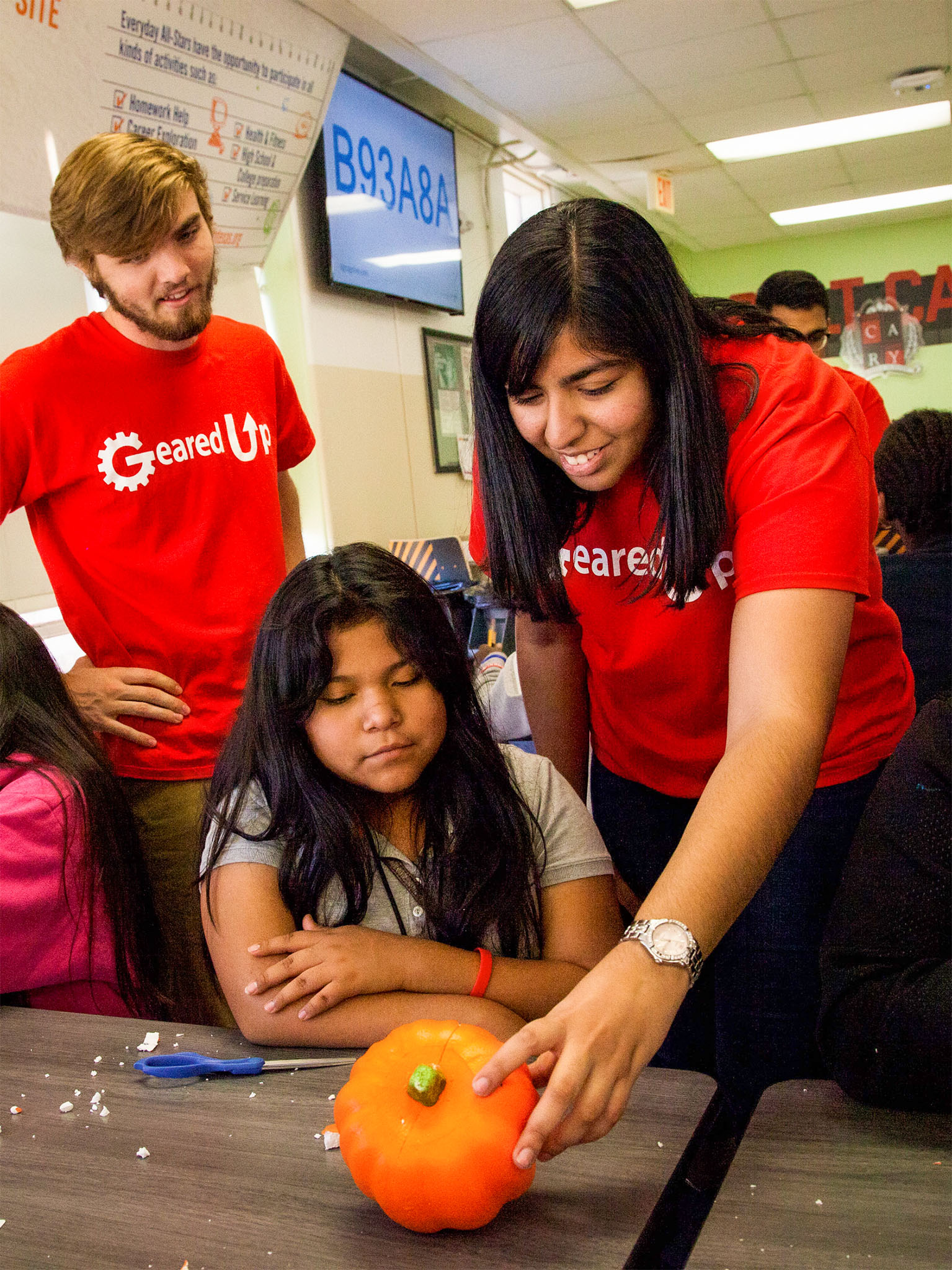 two SMU students painting pumpkin with a child