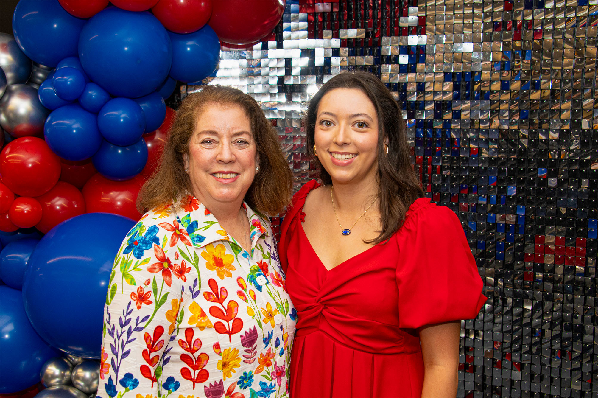 Catherine Ramsey and mom smiling and standing in front of silver sequined wall with red and blue balloons